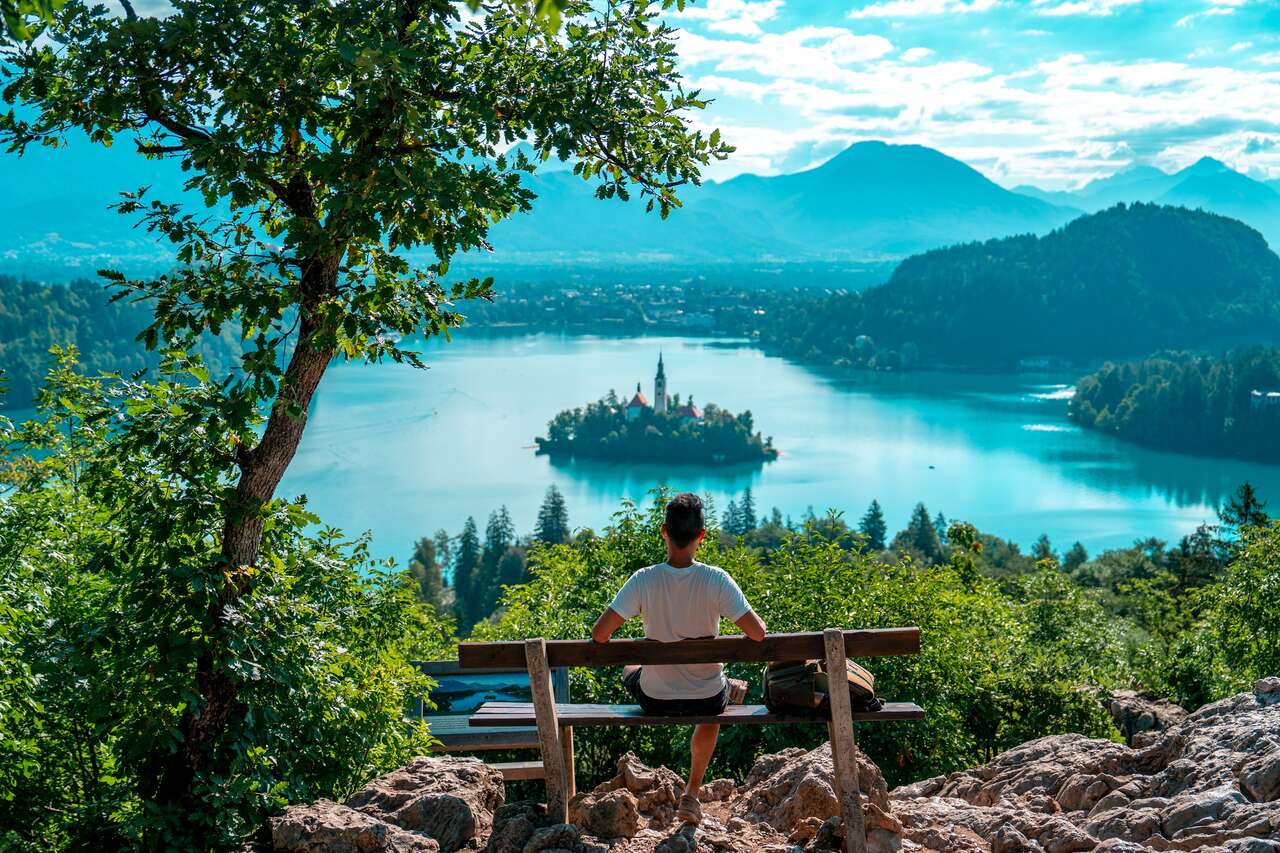 A person sitting on a bench looking at Lake Bled from Ojstrica