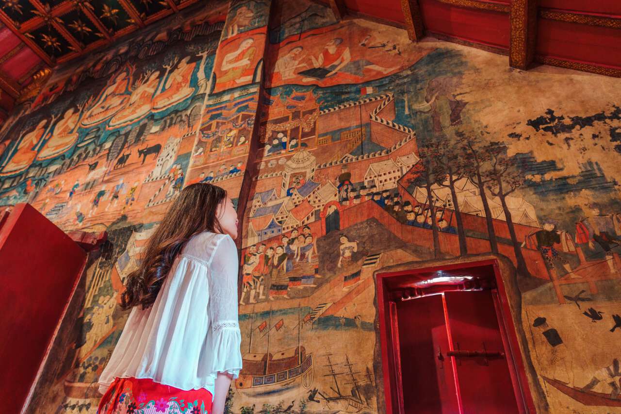 A person looking at the murals in Wat Phumin in Nan